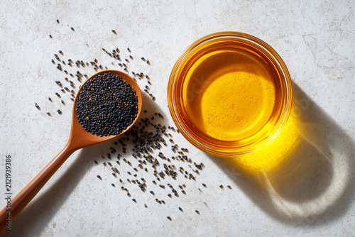 Mustard Oil in Glass Bowl with Seeds on Wooden Spoon Flat Lay