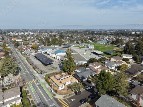 Aerial view of residential neighborhood in Cupertino, California with suburban homes and distant mountains. g.
