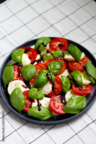 Caprese salad on a black plate with balsamic vinegar