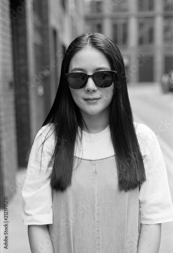 Canvas Print Young woman wearing sunglasses smiling on urban street
