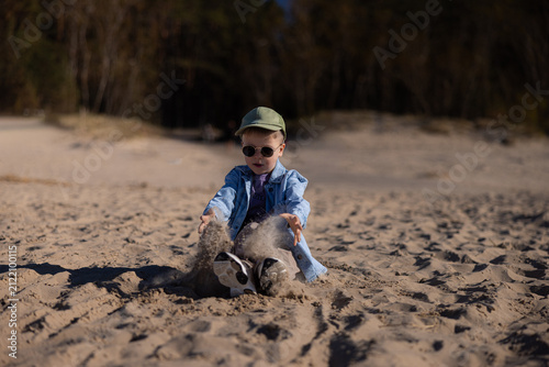 Konstfotografi Child playing on sandy beach in Jurmala, Latvia, wearing sunglasses and a cap, j