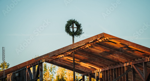 Traditional topping-out wreath mounted on a timber-framed house under construction, marking an important milestone in the residential building process.