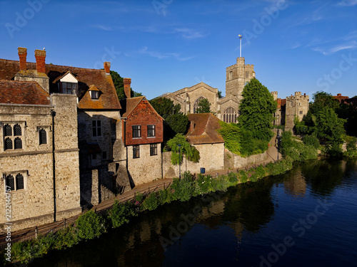 Gothic church and Archbishop's Palace by the river Medway in Maidstone, Kent. Beautiful historic buildings at golden hour with blue sky. Quiet pedestrian walk by the river. Maidstone, UK, 05.26.2026