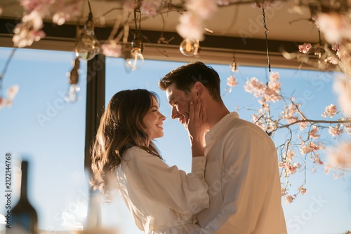 Romantic young couple dancing together by window during intimate evening