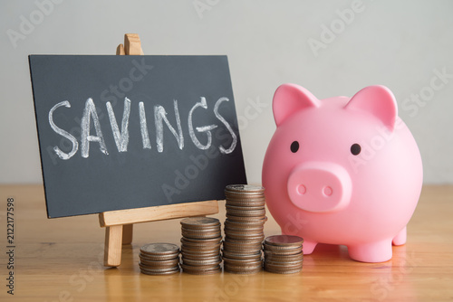 Pink piggy banks, stack coins and SAVINGS hand writing in blackboard on table. Financial planning management, money literacy, savings, personal wealth, money saving, banking finance and so on concept.