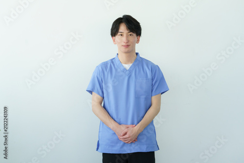 Obraz w ramie 白背景のスクラブを着た若い日本人男性整体師