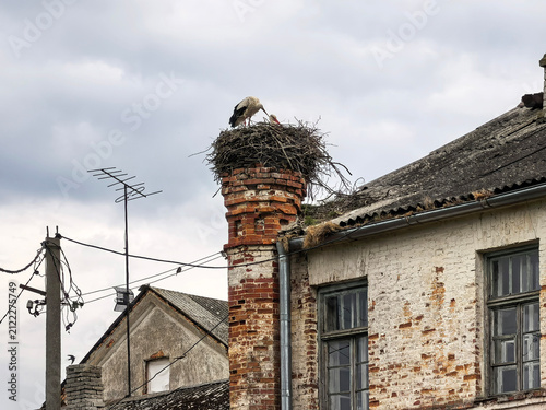 White storks with a chick on a nest in one of the towers of an outbuilding with a Gothic façade. Lyubcha village, Novogrudok district, Grodno region, Republic of Belarus