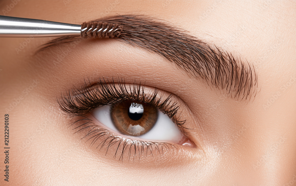 Naklejka premium Young woman correcting eyebrow shape with brush, closeup