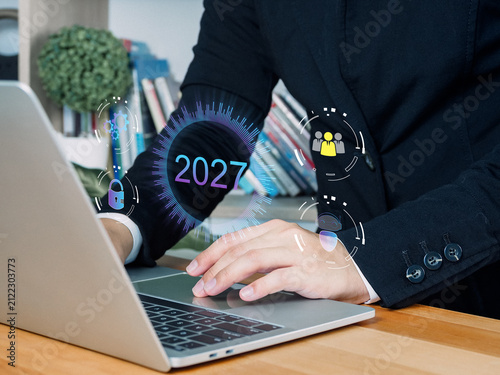 Laptop computer business person typing with digital interface showing 2027 office workspace technology concept future year online security data protection communication innovation finance