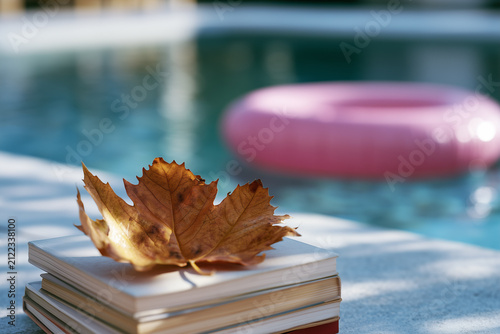 An autumn maple leaf lies by the pool next to an inflatable ring. The start of the school year. The end of summer.