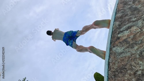 Young man performs impressive backflip into a sparkling blue swimming pool