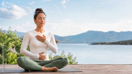 Woman practicing a breathing technique for anxiety relief outdoors. Female meditating on a wooden deck with mountain views. Mindfulness and mental wellness concept