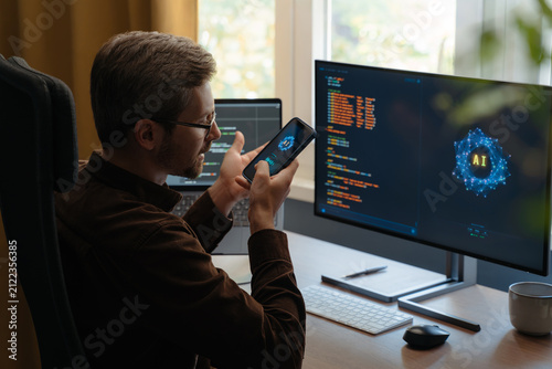 Фотография Programmer communicating with an AI agent through a smartphone, using a voice digital assistant on phone for software development and vibe coding