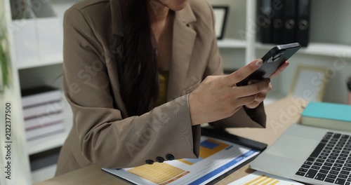 Businesswoman using a smartphone to review financial information, manage business communication, and access digital reports in a modern office, supporting mobile productivity and business management.