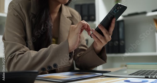 Businesswoman using a smartphone to review financial information, manage business communication, and access digital reports in a modern office, supporting mobile productivity and business management.