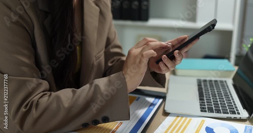 Businesswoman using a smartphone to review financial information, manage business communication, and access digital reports in a modern office, supporting mobile productivity and business management.