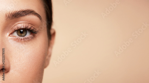Beautiful woman half face close up portrait with copy space on beige background
