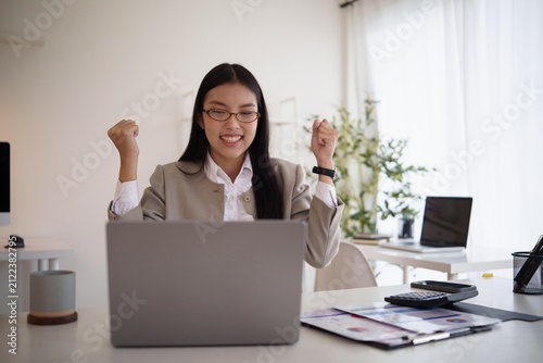 Принти на полотні Excited businesswoman celebrating success while working on laptop in a bright modern office