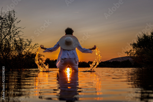 Quadro su tela Person splashing water in lake feeling freedom and relaxation at summer sunset