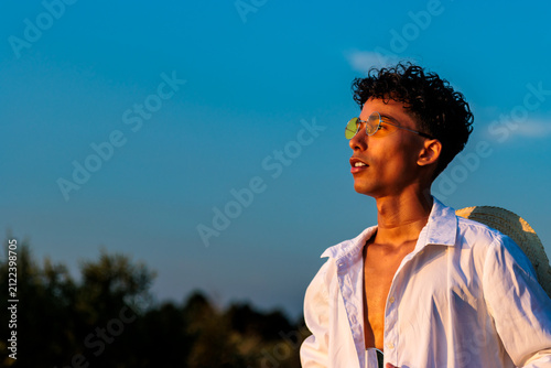 Young man enjoying summer freedom under blue sky at golden hour sunset
