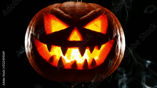Glowing Halloween Jack-o'-lantern pumpkin with scary face and smoke on