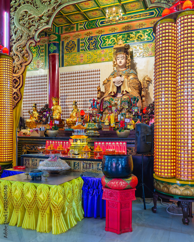 Golden Mazu statue inside the ornate Thean Hou Temple in Kuala Lumpur, Malaysia, featuring traditional religious architecture and decorative prayer altars with offerings