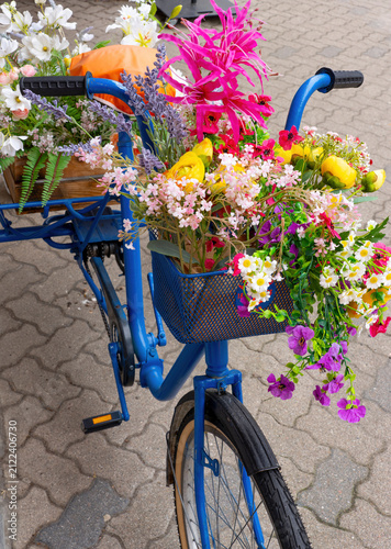 Foto Colorful bicycle basket filled with decorative spring flowers and blossoms