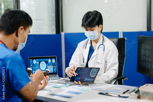Asian medical team reviews brain scan data and clinical reports during a neurology research meeting, highlighting healthcare innovation, collaboration and medical analysis.