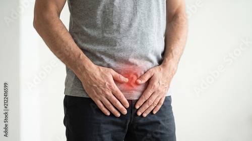 A man experiencing pain in his lower abdomen or groin area, highlighting discomfort and potential medical issues.