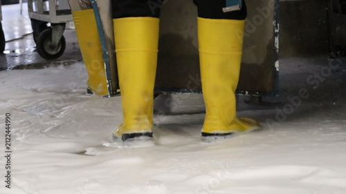 Bild auf Leinwand Close view of worker lower legs in tall yellow rubber boots standing on soapy we