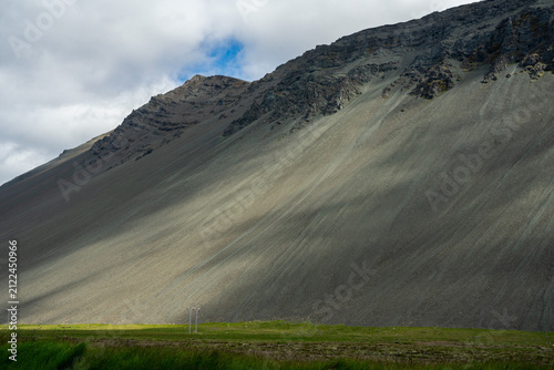 Massive mountain slope with scree texture under a cloudy sky in Iceland.