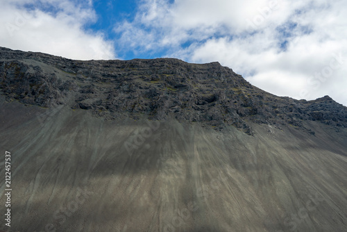 Close-up of a massive volcanic mountain cliff with scree slopes in Iceland.