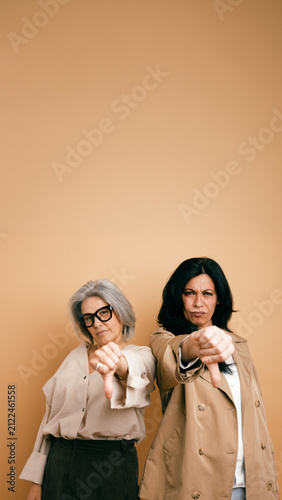 Photography Two mature women expressing rejection or disapproval with a thumbs down gesture,