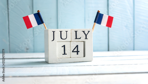 Wooden calendar blocks showing july 14 date with small french flags, fourteenth