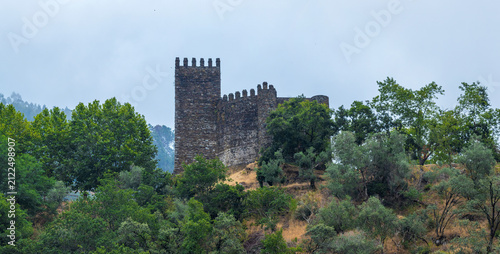Принти на полотні An ancient stone castle tower with battlements stands dramatically on a forested