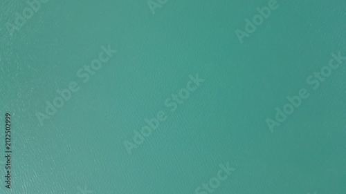 Top-down aerial view of smooth deep-green water surface.