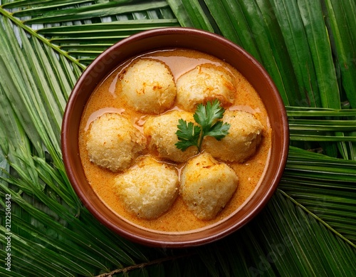 delicious malabar style kozhi pidi in brown bowl with tender rice dumplings in roasted coconut chicken curry on green palm leaves background