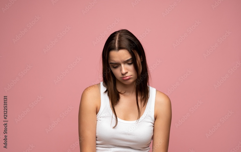 Obraz premium Unhappy young woman feeling sad and depressed, experiencing disappointment and negative emotions on pink background