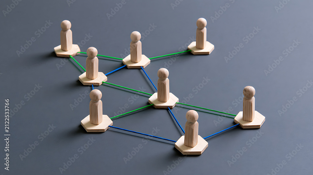 Obraz premium Wooden figures connected by colored elastic bands on a gray surface, representing teamwork, communication, and business network structure