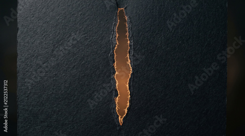 Torn dark paper with amber light slit. Ripped black cardboard revealing glowing orange gap.