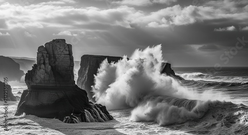 Dramatic black-and-white photograph of powerful ocean waves crashing violently against rugged coastal rock formations under a stormy sky, showcasing raw natural force and dramatic contrast.