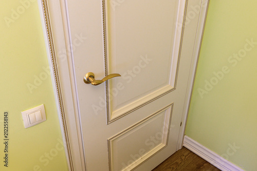 cream‑colored paneled interior door with delicate beaded trim and a polished gold lever handle