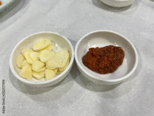 하얀색 작은 종지에 담긴 마늘과 쌈장