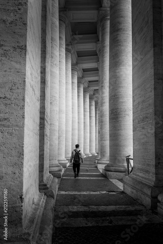 Canvas Print Silhouette walking through black and white colonnade
