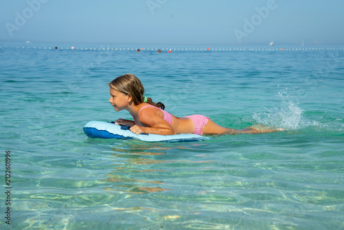 Foto Young Girl in Pink Swimsuit Floating on Bodyboard