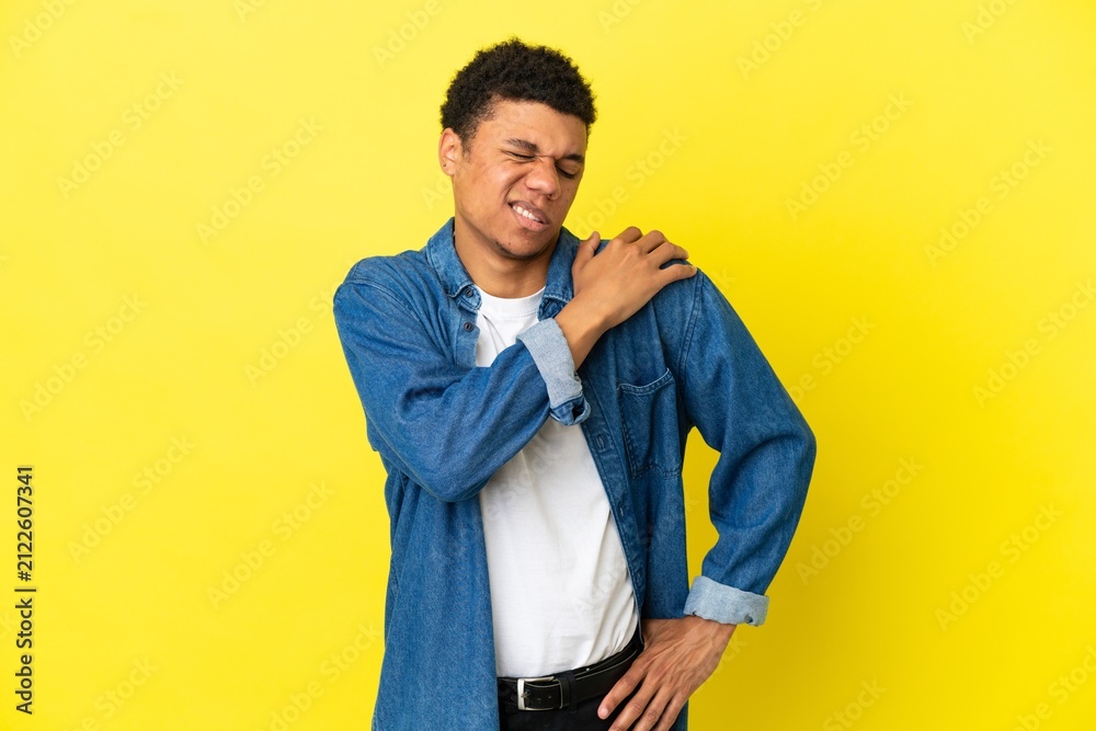 Fototapeta premium Young African American man isolated on yellow background suffering from pain in shoulder for having made an effort