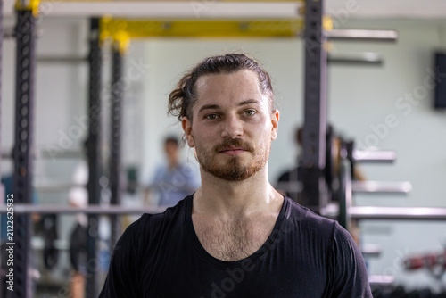 Portrait of caucasian muscular man with perfect abs and bicep muscle inside gym with dark background for exercise and workout in high contrast low key lighting studio
