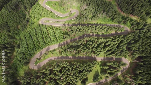 Aerial view of cars driving along the winding Transalpina road through conifer forests in Romania