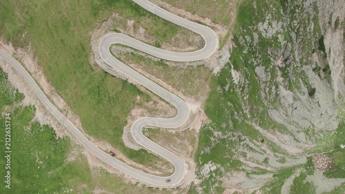 Aerial tracking shot of a car driving on the winding Transalpina mountain road in Romania