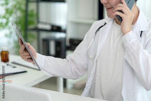 Asian Male Doctor Consulting Patient via Telemedicine Call While Reviewing Digital Medical Records